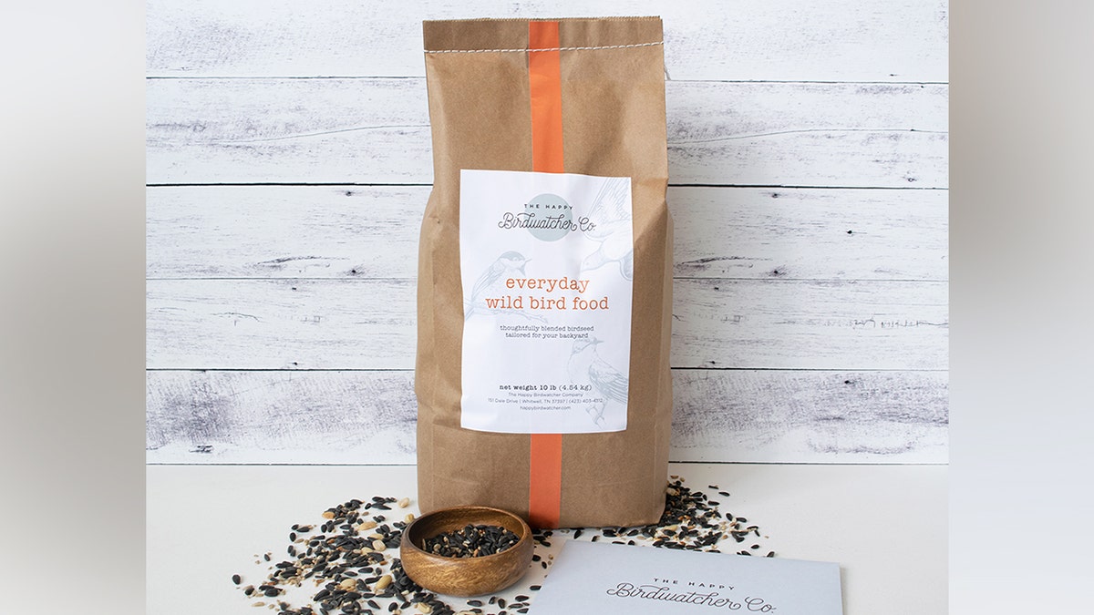 A product image of everyday wild bird food in a brown bag with seeds and a card on the table.