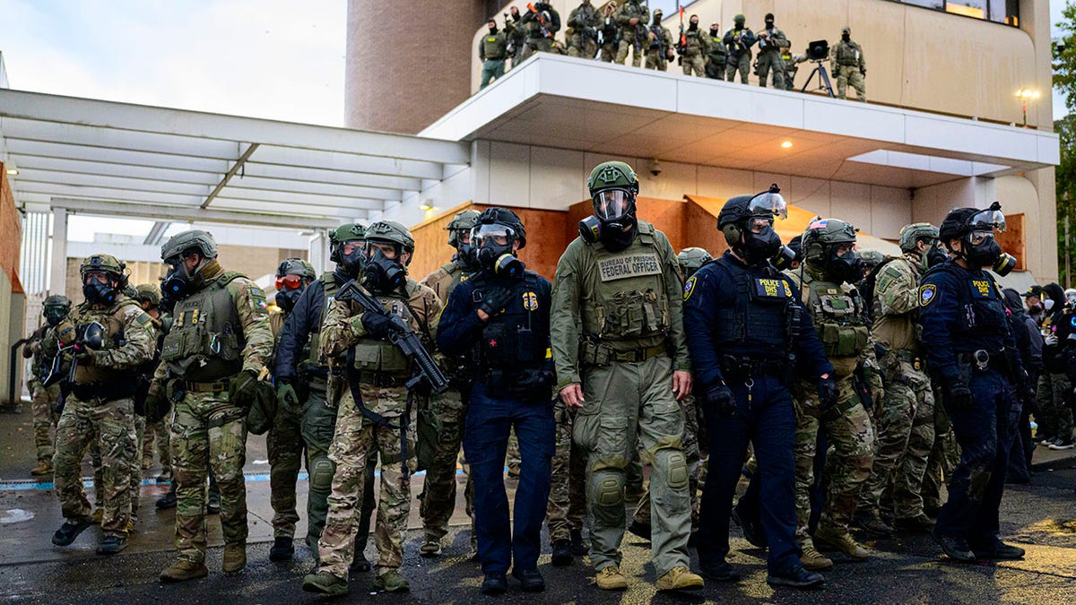 Federal agents stand outside an ICE facility in Portland, Ore.