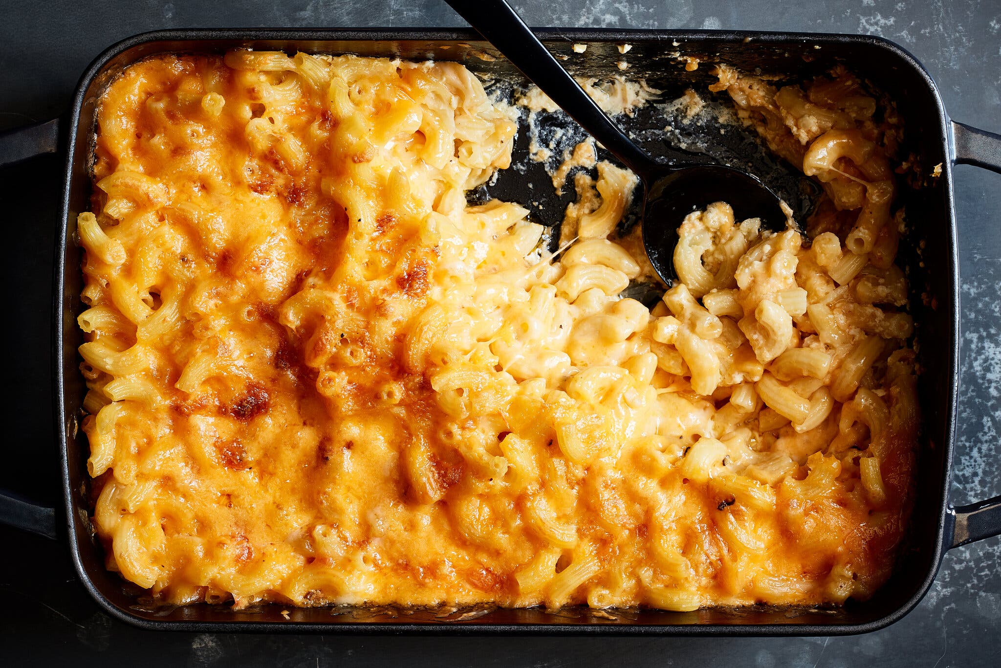An overhead image of gooey, golden-brown macaroni and cheese with a couple of servings removed from one corner.