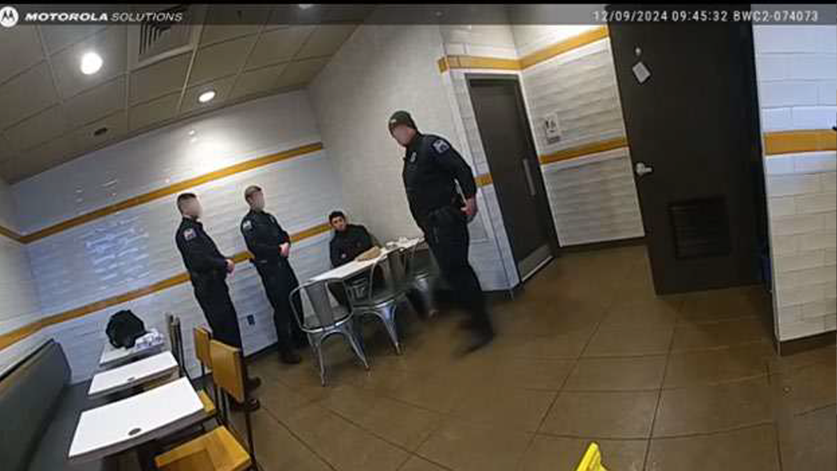 A man identified as Luigi Mangione speaks with three police officers