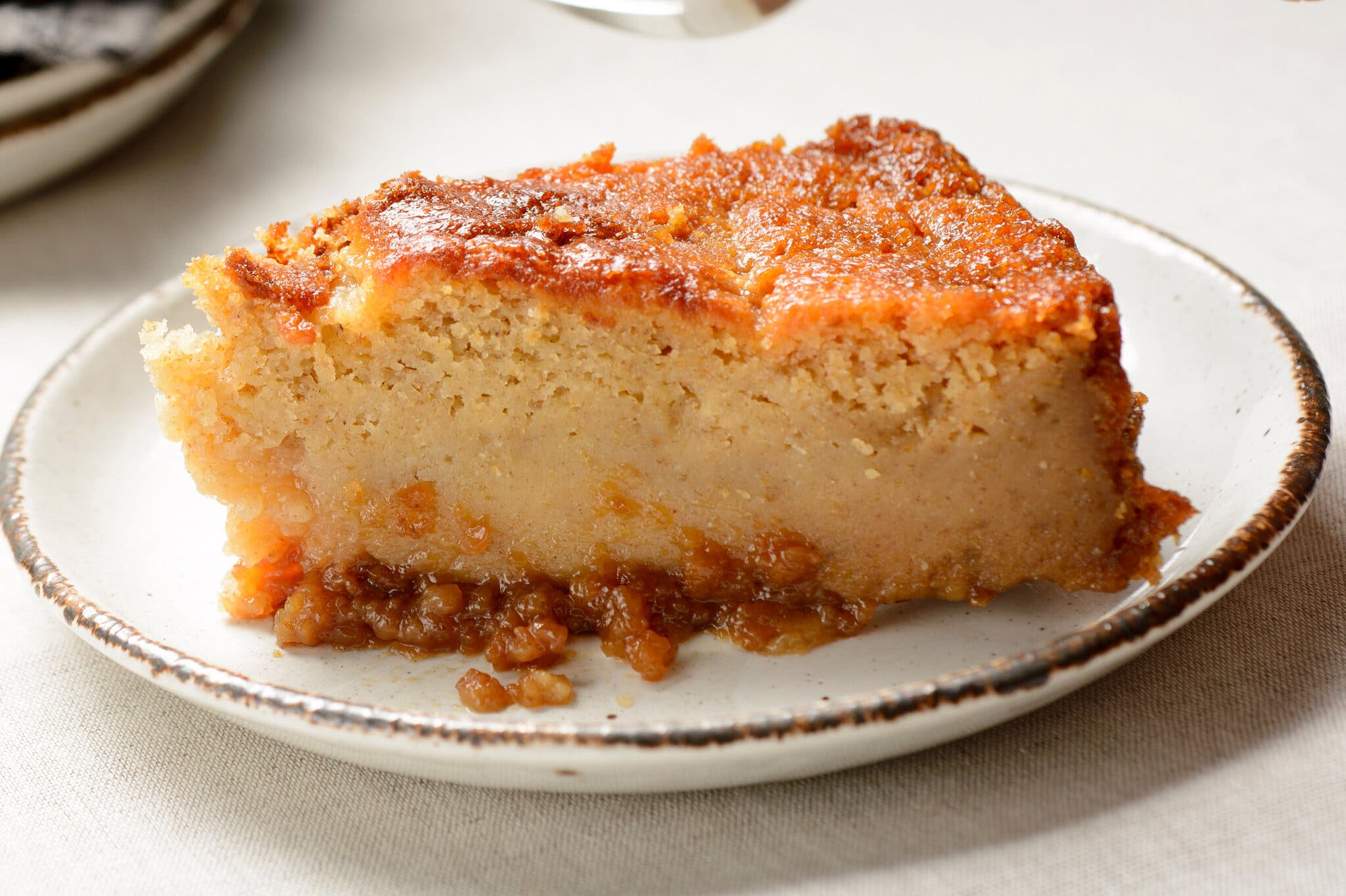A pudding slice on a white plate with an orange-hued top.