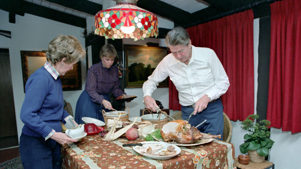 President Ronald Reagan carves a Thanksgiving turkey alongside his family on November 26, 1981.