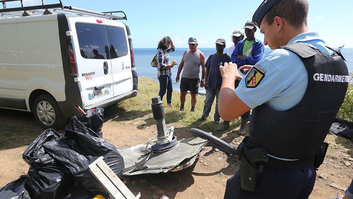 A French Gendarme takes a picture of debris gathered by members of local ecological associations and volunteers on August 11, 2015 in the eastern part of Sainte-Suzanne, on France's Reunion Island in the Indian Ocean, during search operations for the missing MH370 flight conducted by French army forces and local associations. The hunt the missing MH370 resumes on Dec. 30.