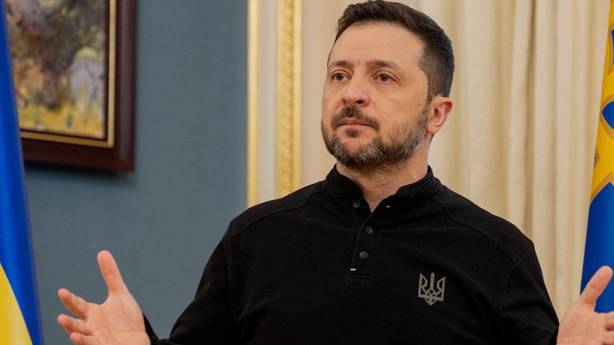 Volodymyr Zelenskyy with his hands raised.