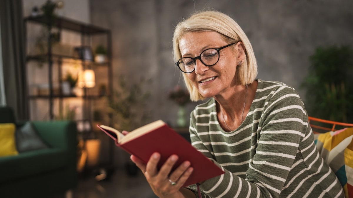 woman holds Bible in her hands, reading it with glasses on