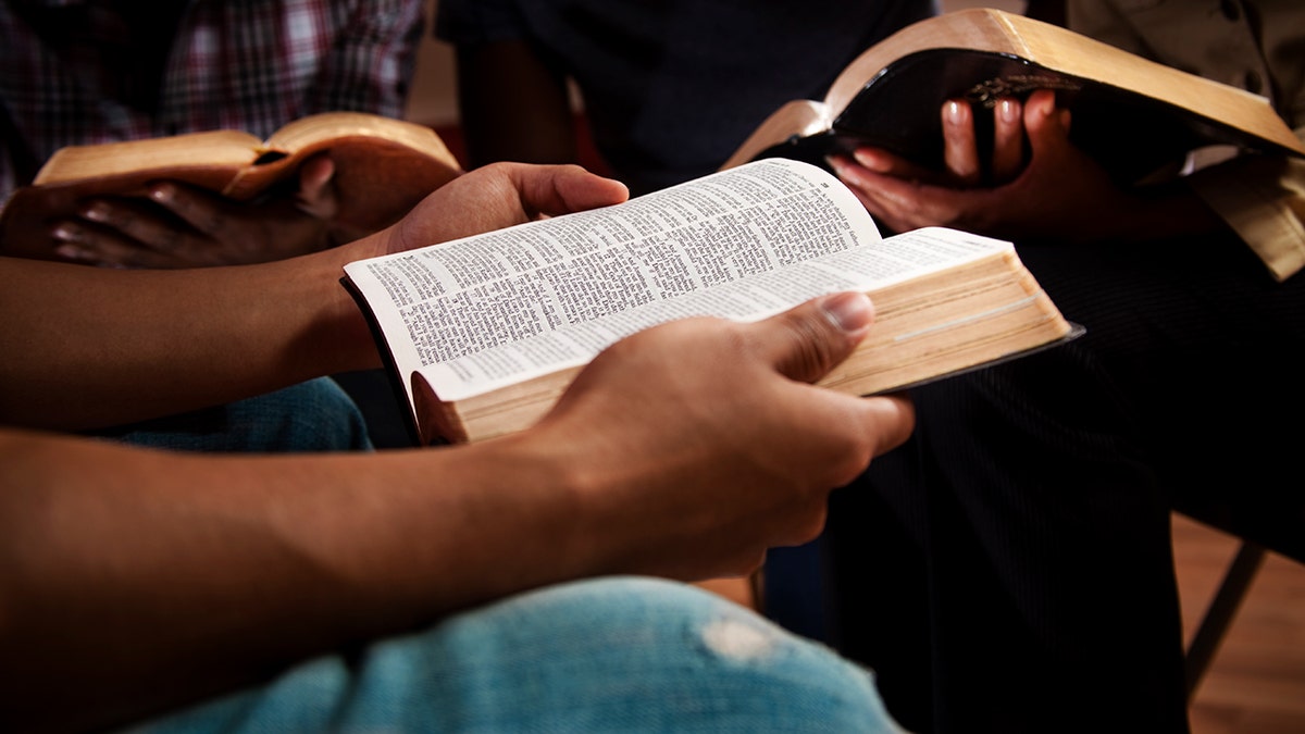 Group of people sitting together and reading open Bibles during a small group study.