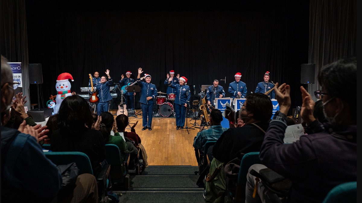 U.S. Air Force Band of the Pacific members wave goodbye during a holiday concert at Tama Hills, Japan, Dec. 13, 2025. The event emphasized mutual respect and collaboration between the U.S. and Japanese communities through music.