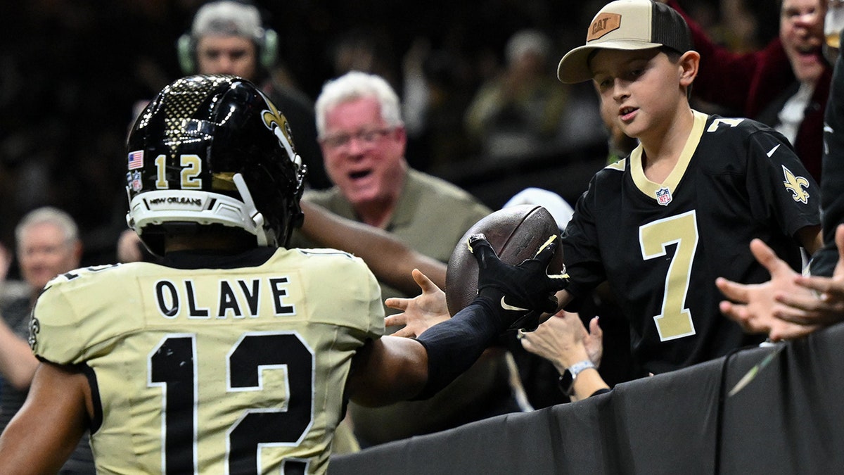 Chris Olave gives a ball to a fan
