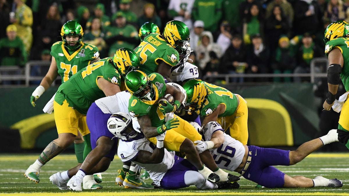 Oregon Ducks running back Jordon Davison (0) runs the ball against James Madison Dukes defensive lineman Xavier Holmes (9) and linebacker Drew Spinogatti (56) during the College Football Playoff first round game between the Oregon Ducks and James Madison Dukes on December 20, 2025 at Autzen Stadium in Eugene, Oregon.