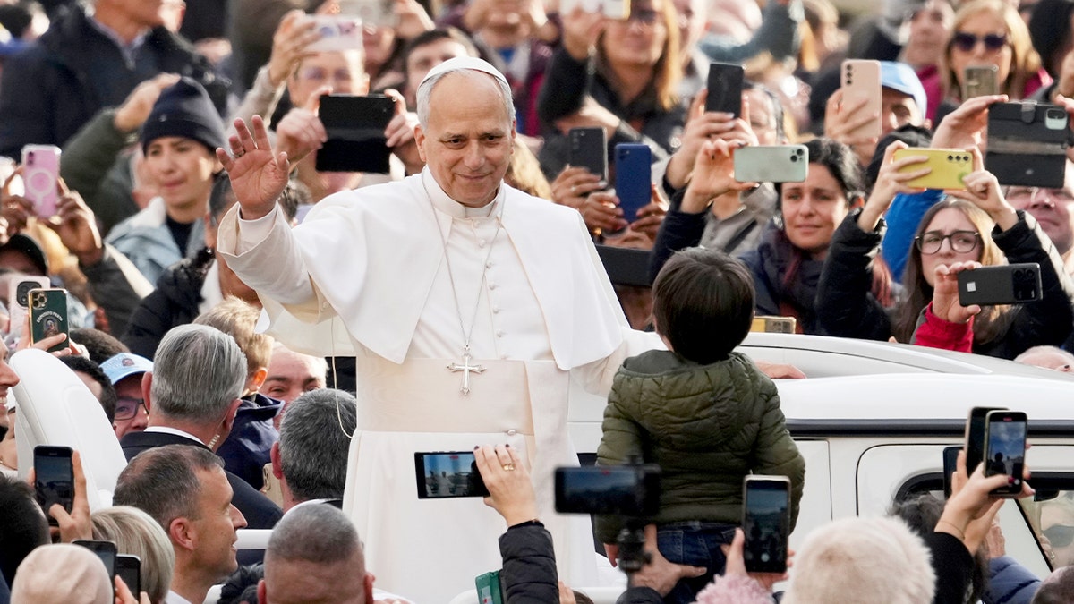 A pontiff in white robes greets the crowd during a public audience in St. Peter’s Square.