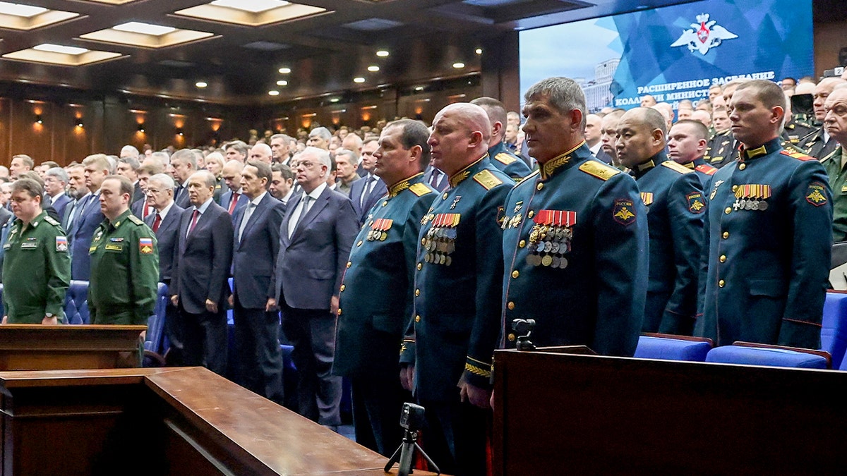 Uniformed service members observe a moment of silence during a formal military gathering.