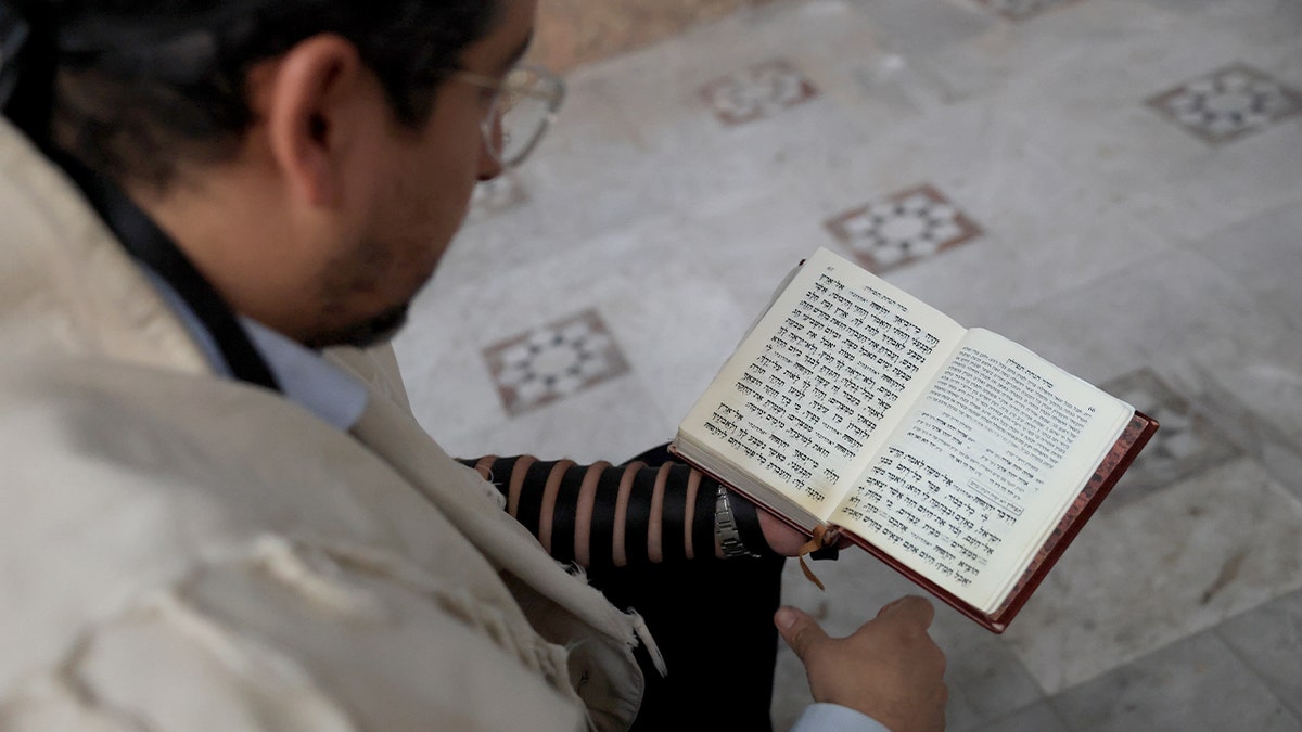 A rabbi prays while holding a document during a ceremony in Damascus.