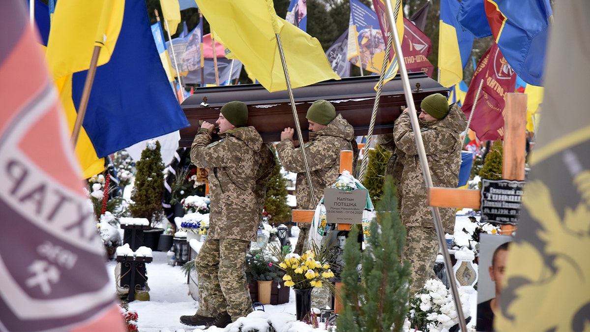 Soldiers bear a flag-draped coffin through a cemetery during a military funeral in Lviv.