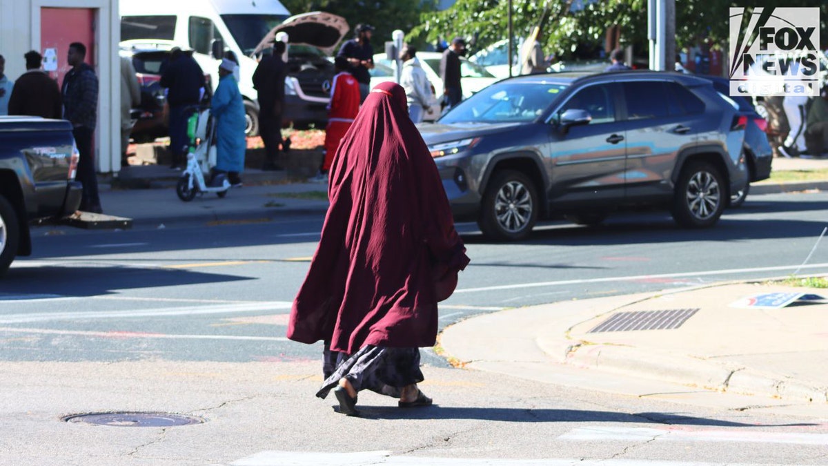 Woman in maroon abaya crossing street near mosque in Cedar–Riverside Minneapolis
