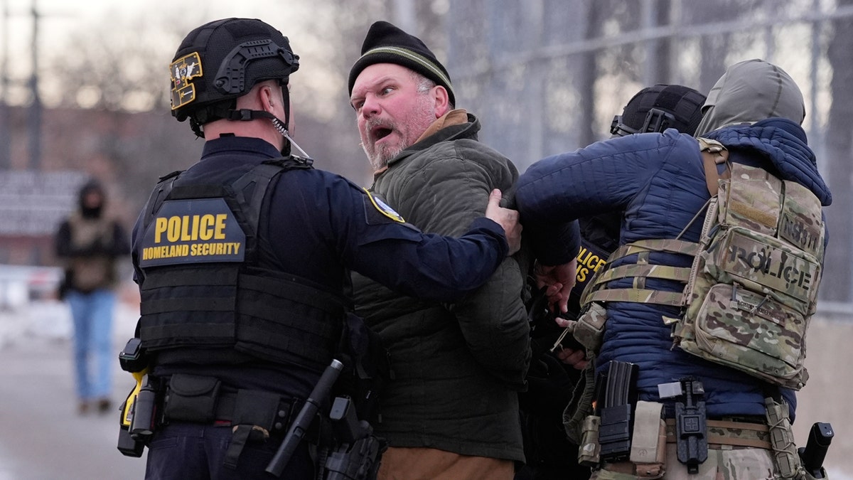 Federal officers detain a man as he yells at officer