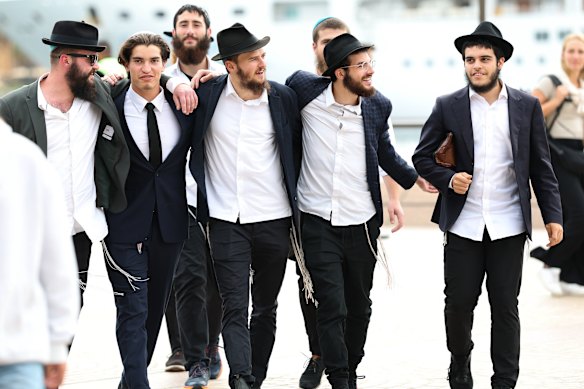 A group of men wrap their arms around one another as they enter the Opera House.