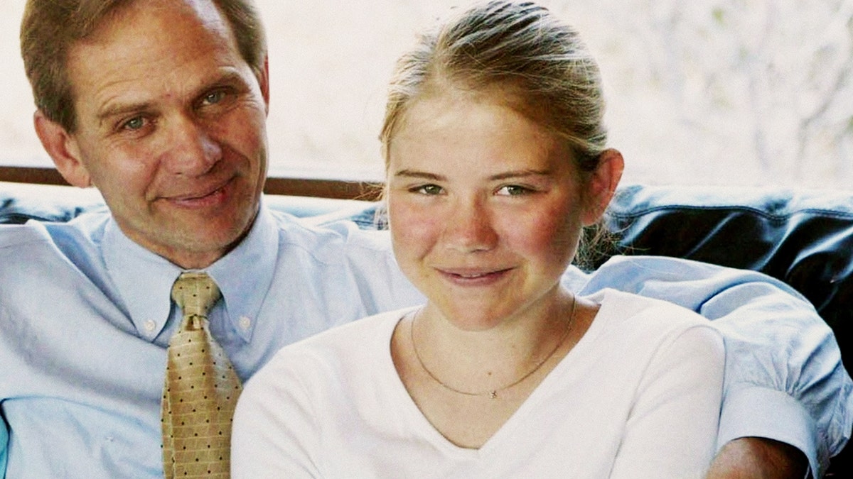 Elizabeth Smart wearing a white shirt and being embraced by her father.
