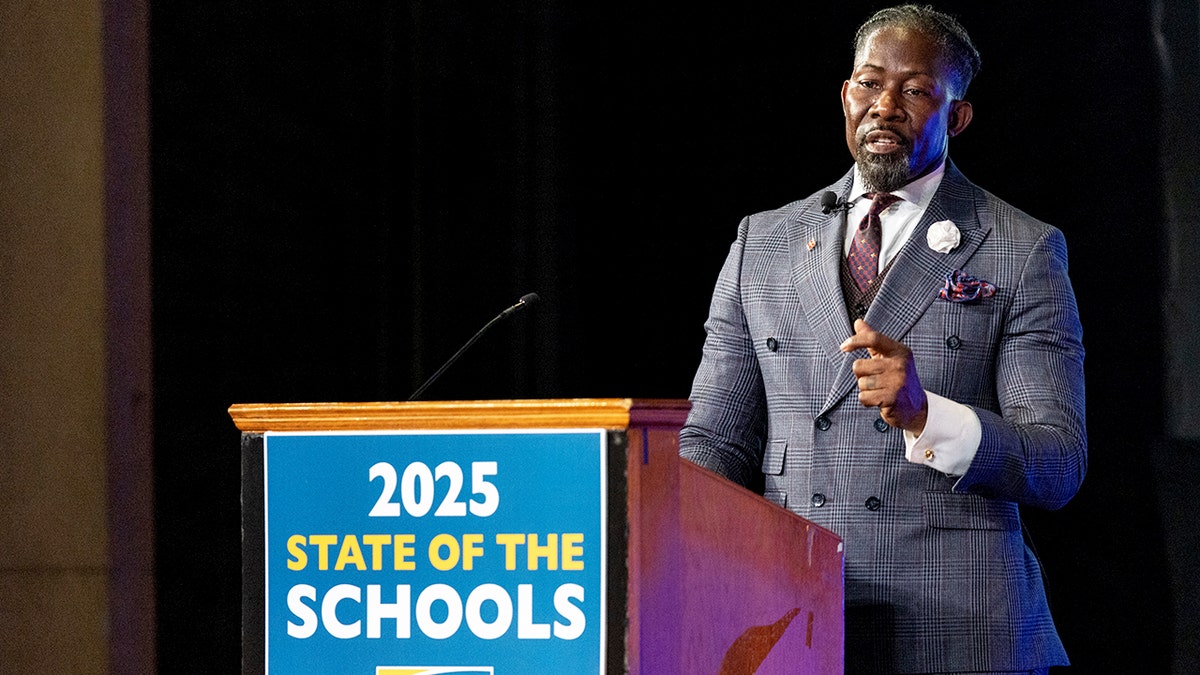 Ian Roberts speaks at podium at high school in Iowa.