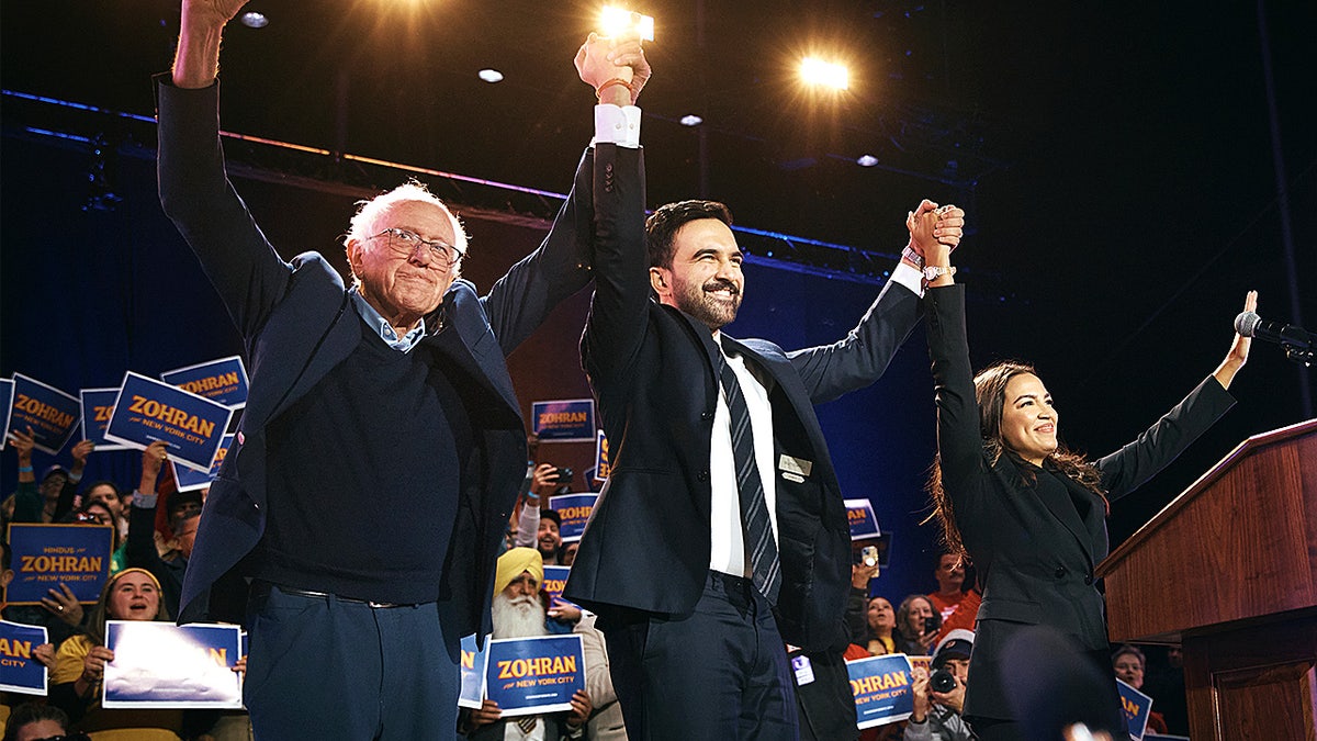 Zohran Mamdani celebrates on stage with Bernie Sanders and Alexandria Ocasio-Cortez during a campaign rally in Queens, New York.