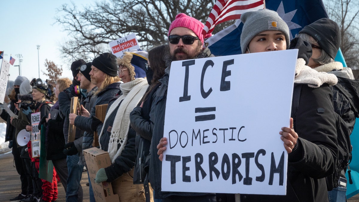 Protesters hold a sign that reads ICE = Domestic terrorism
