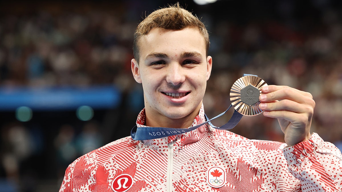 Ilya Kharun holds up the bronze medal in Paris