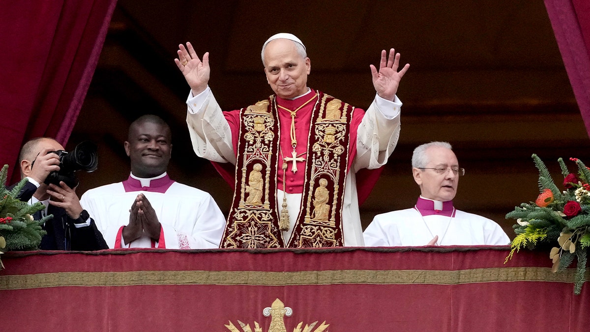 The pope raises his hand in farewell from a balcony above a large crowd gathered in St. Peter’s Square.