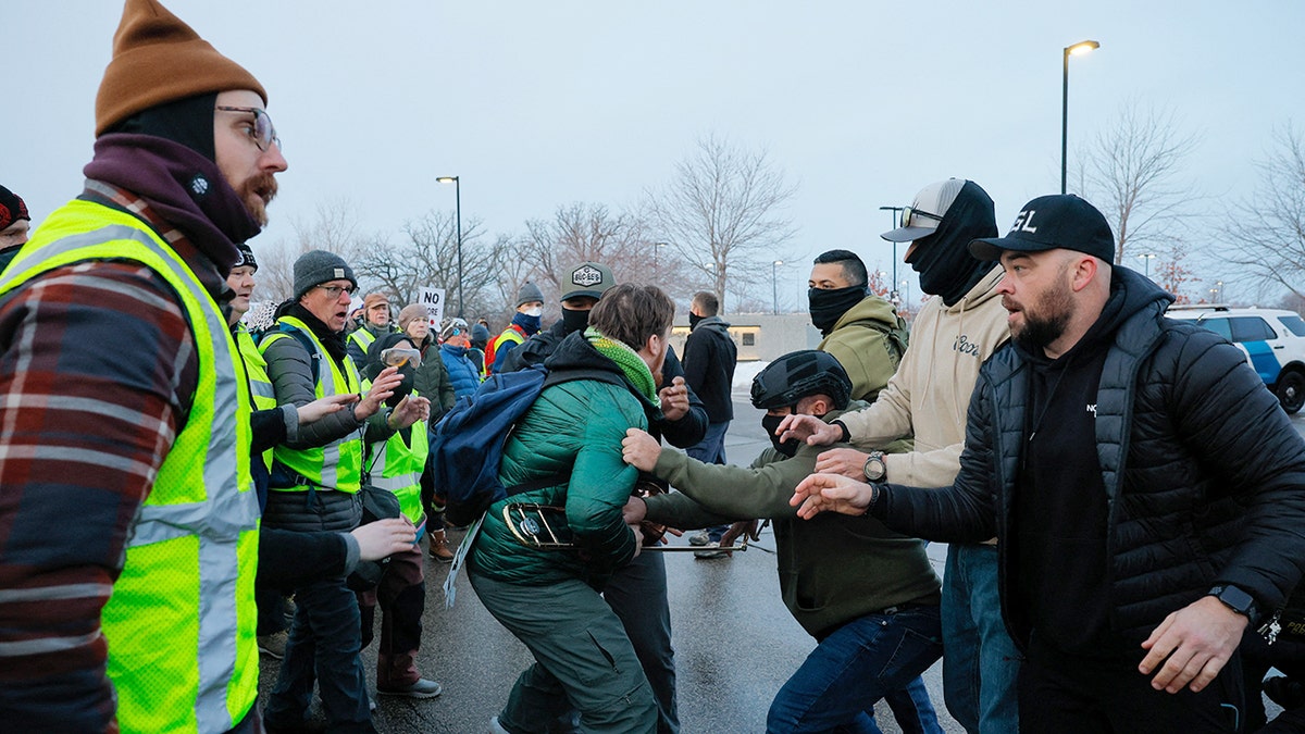 Law enforcement officers restrain a protester as demonstrators gather outdoors during a confrontation in Minneapolis.