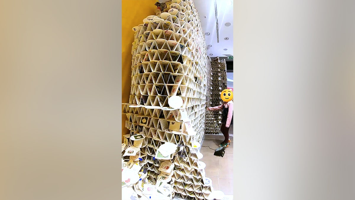 A young girl reaching to touch a beer coaster tower