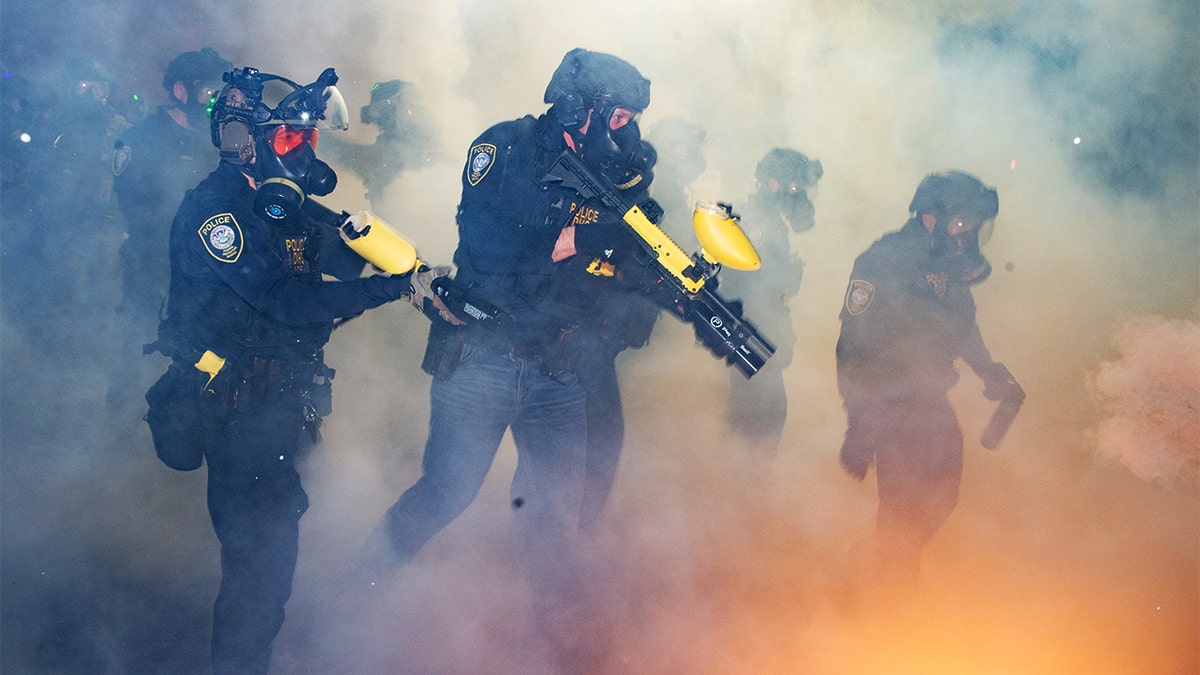 Crowd-control weapons are fired as a large group of demonstrators approaches a secured federal facility in Portland.