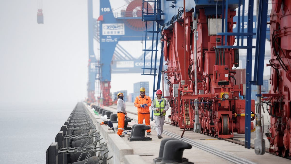 Workers in Lima, Peru, stand next to cranes at the new megaport being built by China