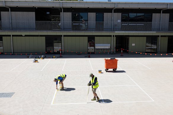 Workers painting lines for the school’s handball courts.