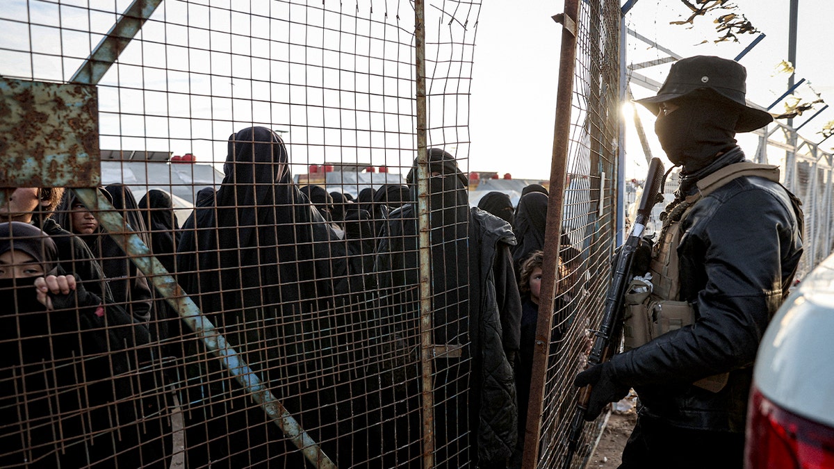 People stand inside a remote camp holding displaced families.