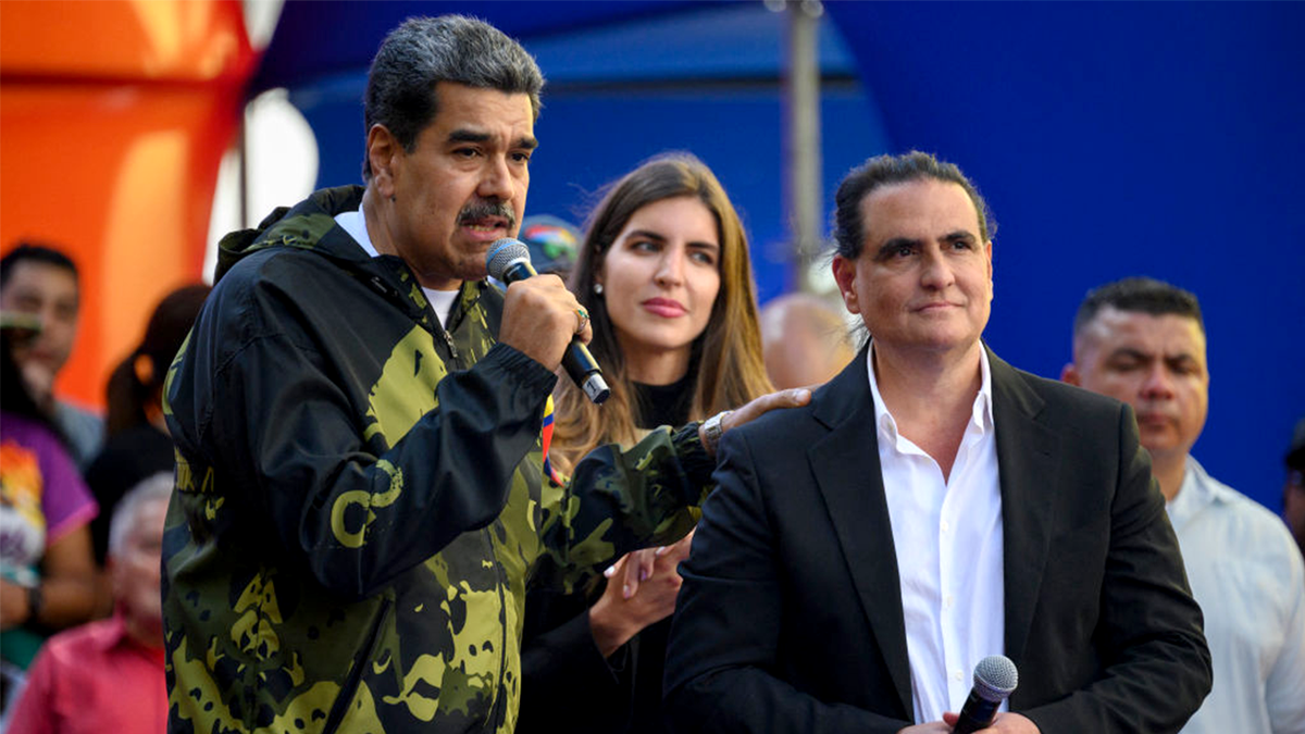 Venezuela's then-President Nicolas Maduro speaks to supporters next to Colombian-born businessman Alex Saab