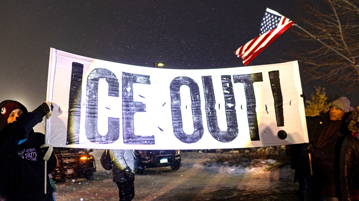 minneapolis protestors at night with ICE OUT sign