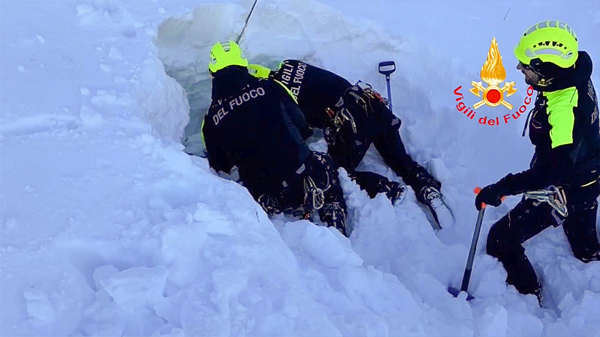 Vigili del Fuoco rescuers work in deep snow during mountain search.
