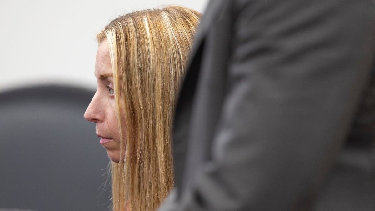 Julie Rizzitello sits in court wearing a red jail uniform
