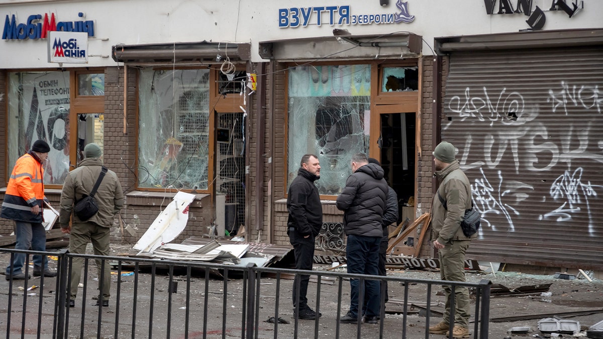 Emergency responders gather outside damaged storefronts in Lviv after deadly nighttime explosions.