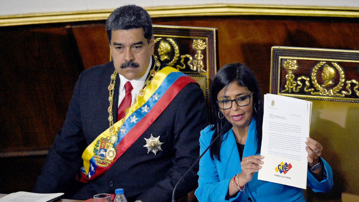 Nicolás Maduro sits beside Delcy Rodríguez during a presidential swearing-in ceremony in Caracas.