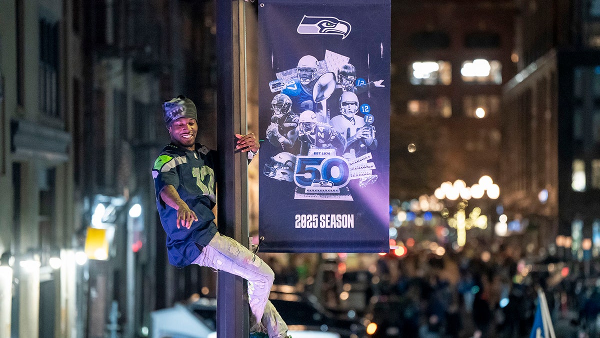 A Seahawks fan climbs a light pole