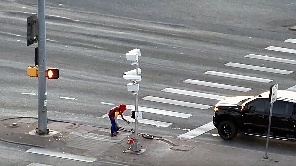 Fire-juggling unicyclist carries his unicycle out of a Colorado intersection.