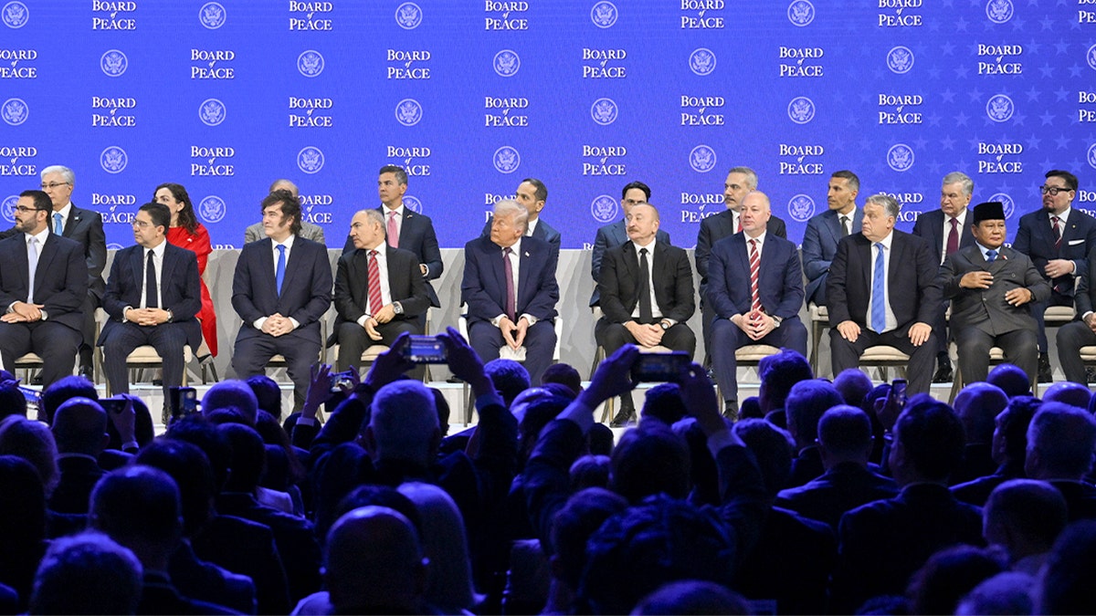 World leaders sit together on a stage during a formal diplomatic ceremony at an international summit.