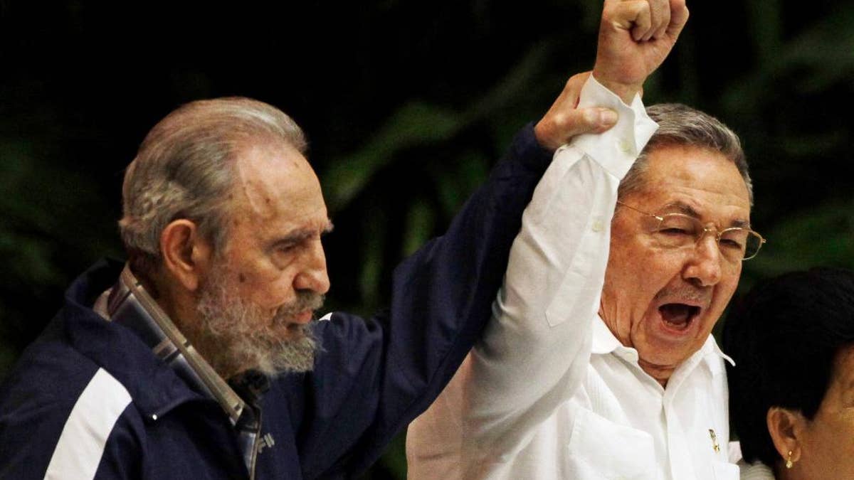 FILE - In this April 19, 2011 file photo, Fidel Castro, left, raises his brother's hand, Cuba's President Raul Castro, center, as they sing the anthem of international socialism during the 6th Communist Party Congress in Havana, Cuba. Cuban President Raul Castro has announced the death of his brother Fidel Castro at age 90 on Cuban state media on Friday, Nov. 25, 2016. (AP Photo/Javier Galeano, File)