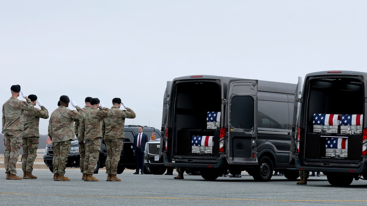 Soldiers salute cars with transfer cases of fallen soldiers
