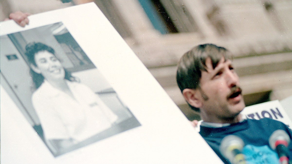Someone holding a photo of Karla Faye Tucker outdoors.