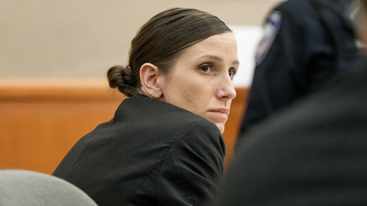 Kouri Richins seated at a table, looking forward during her murder trial.