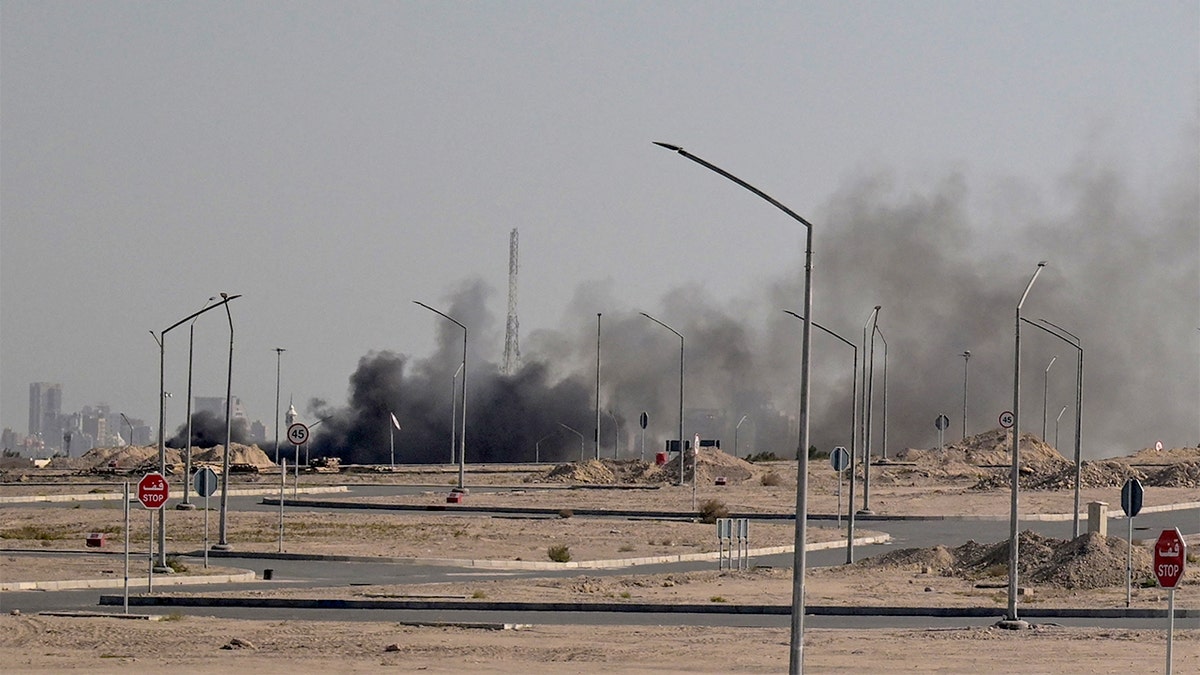 Dark plumes billow into the sky near the U.S. Embassy compound in Kuwait City following reported missile attacks.