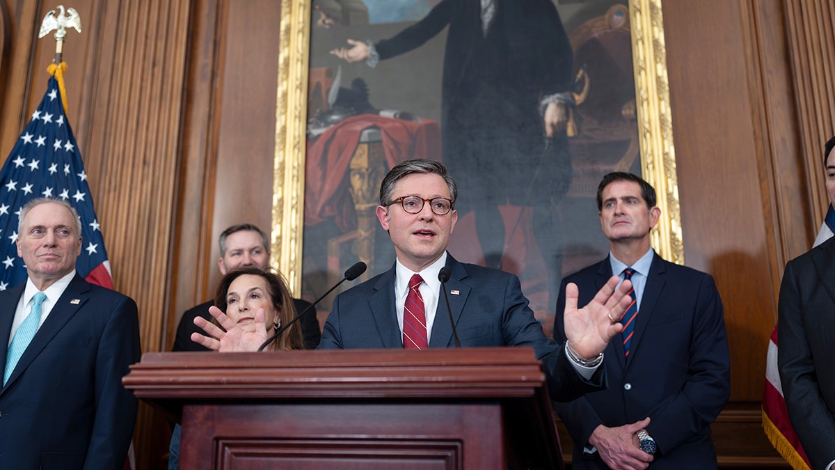 Speaker of the House Mike Johnson speaks from a podium to address reporters