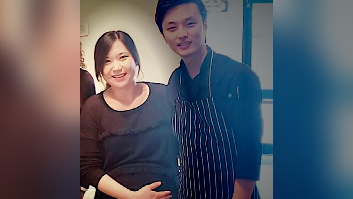 Eina Kwon holds her belly as she stands smiling next to her husbandd
