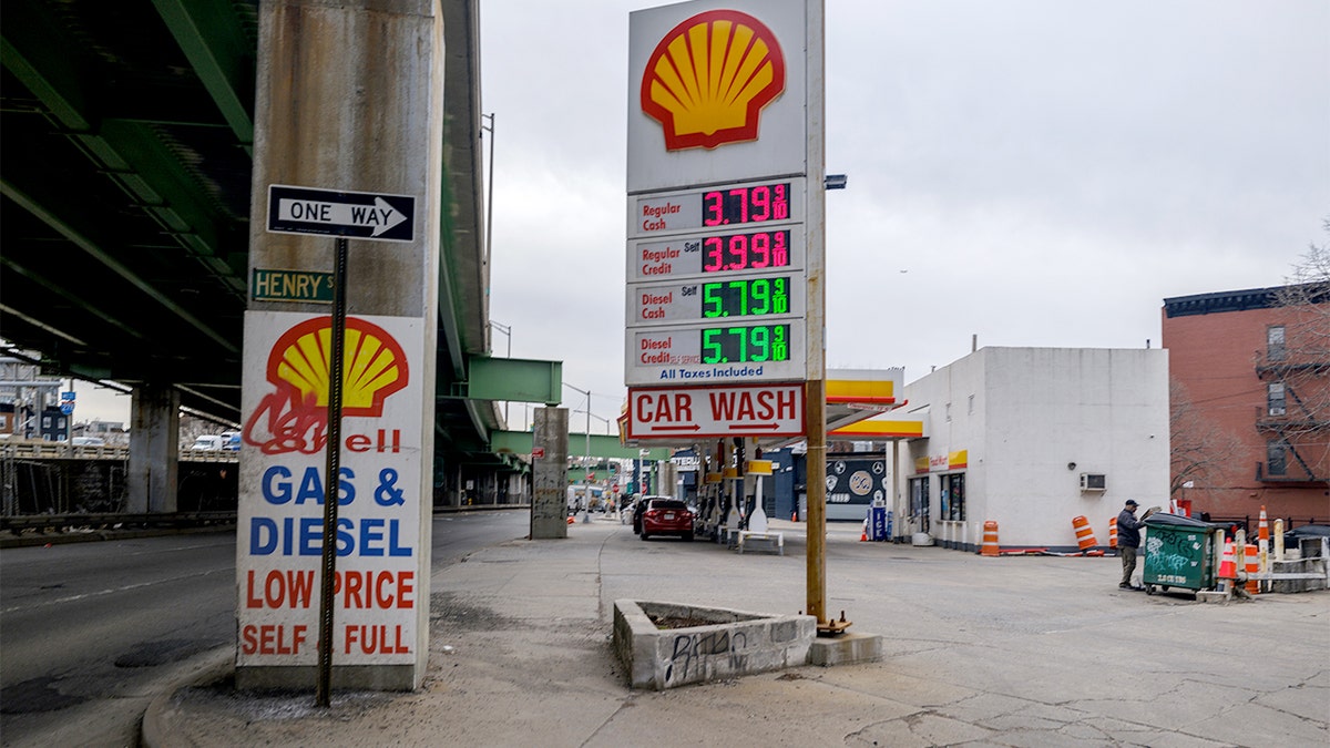 Gas station price boards showing elevated fuel costs in a New York City neighborhood.