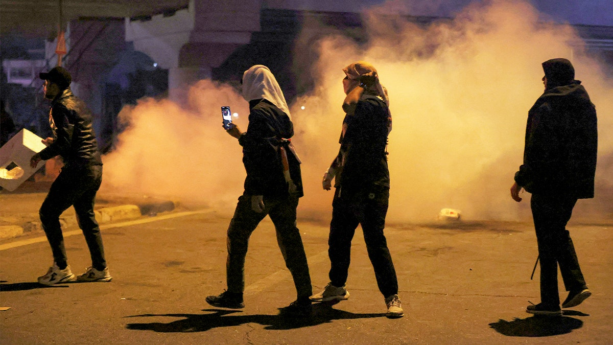 Demonstrators move through clouds of tear gas as security forces block access to a bridge in Baghdad.
